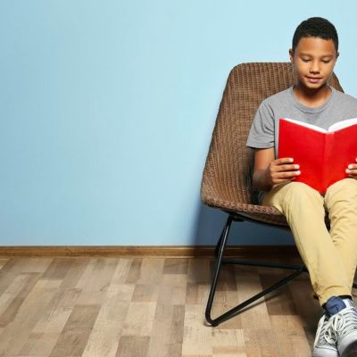 kid reading a book while sitting on a chair