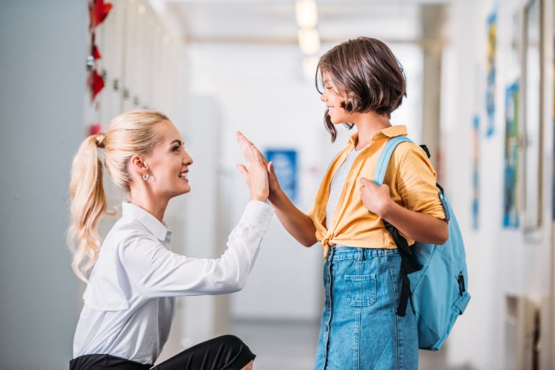 Teacher student culture teacher high fiving a student at her level