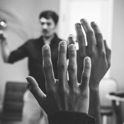 two raised hands, teacher talking in background