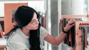 student pulling book from bookshelf