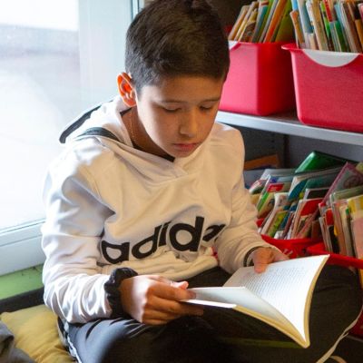 young boy reading a book in a library