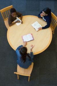 students discussing books at a table
