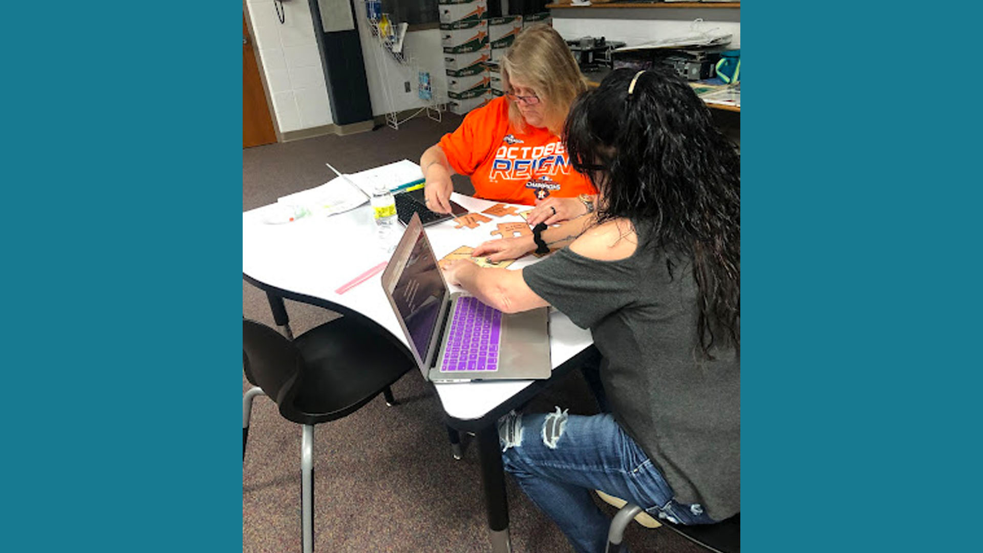 Two teachers working on puzzle pieces.