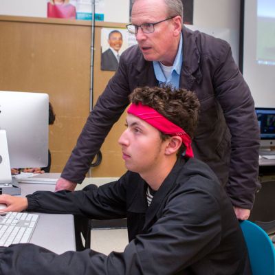 Teacher helps a student at the computer.