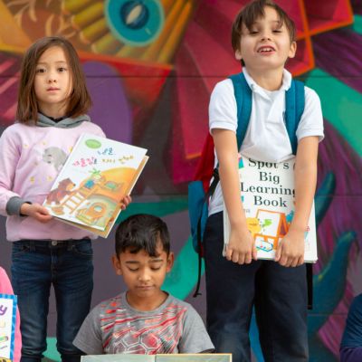 Elementary students with books and school mural