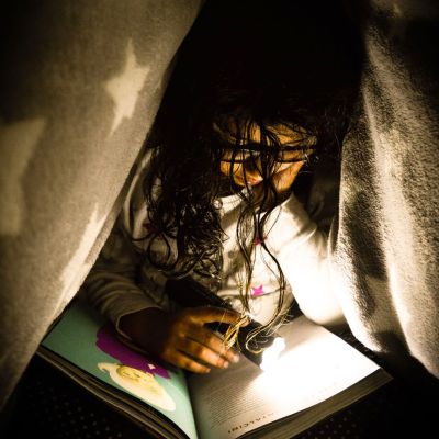 Student reading under a blanket.