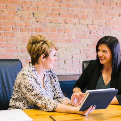 Two women discussing material in a meeting.