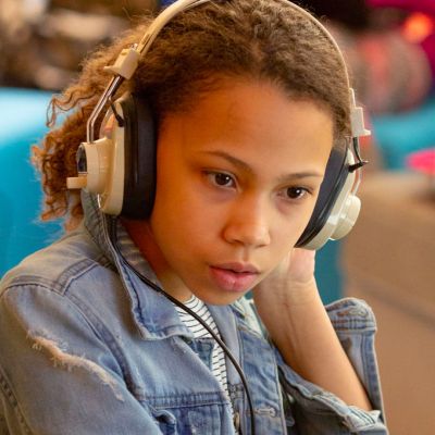 Young female student listen to music in class.
