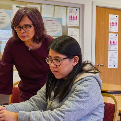 Teacher and student reviewing content on a computer.