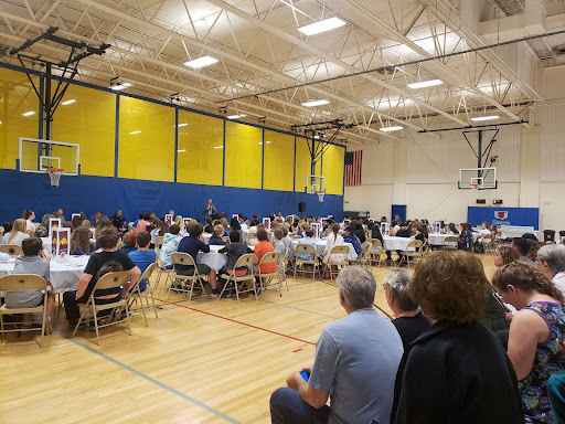 Sitting in a gym Families attending Work Ethic event.
