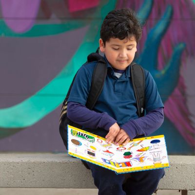 First Grade boy reads book outside.