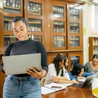 Woman standing and holding a laptop.