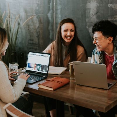 Three people sitting at a table with their laptops.