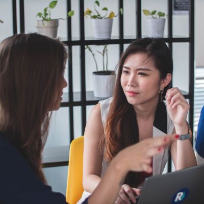 Two women talking, sitting down at a table.