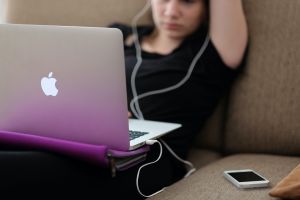 Person sitting down with a laptop on their lap.