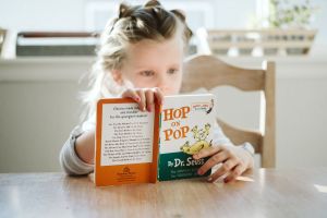 Child reading a book at a table.