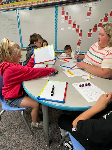 In the Trenches 3 Teacher working with students around a table.