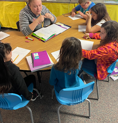 Teacher sitting with students around the table.