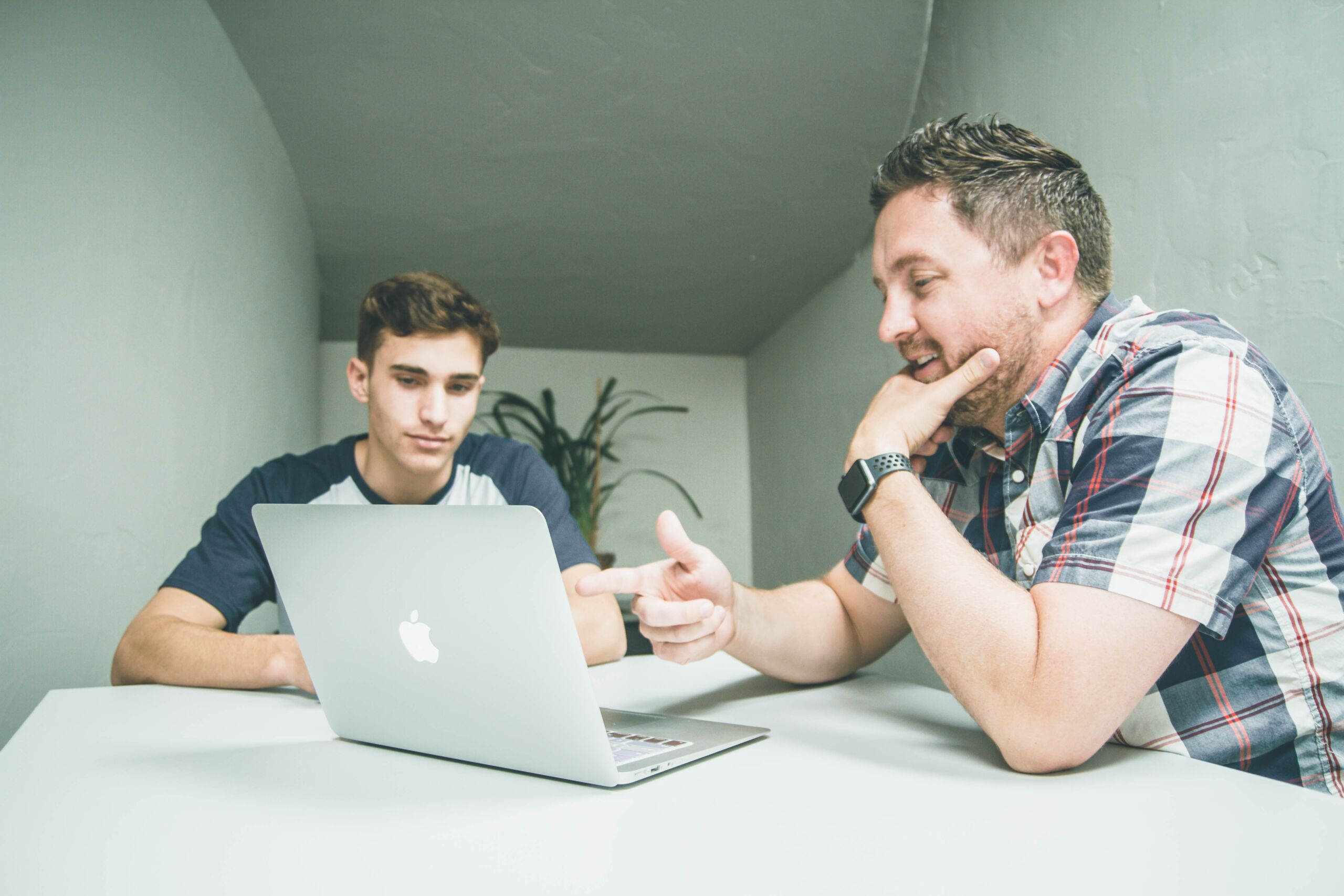 Two people talking, while looking at a laptop.