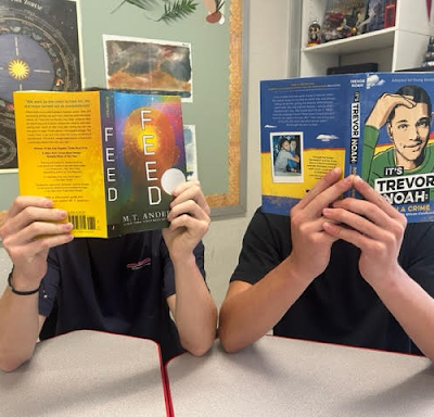 Students holding books up and reading.
