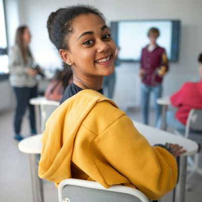 Student posing for a picture, while seated at her desk.