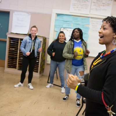 A music teacher leads choir students in a warm-up exercise.