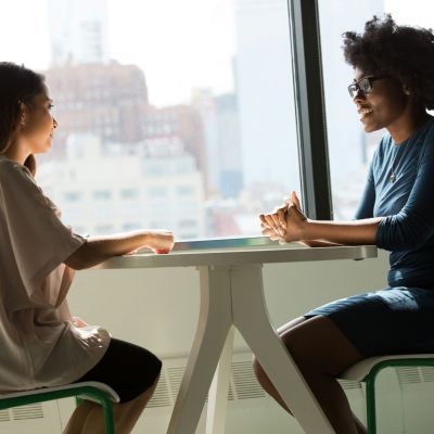 Two women sitting at a table and talking.