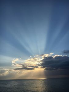 Sun behind the clouds, over the ocean.