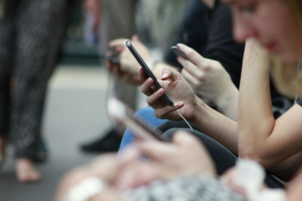 Person holding a black cell phone in their hand.