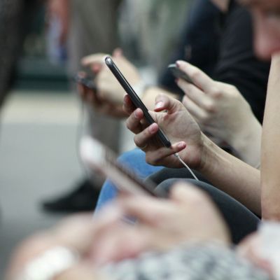 Person holding a black cell phone in their hand.