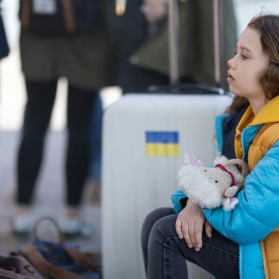 Little girl sitting down, holding a stuffed animal.