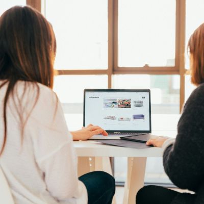 Two women working together in front of a computer.