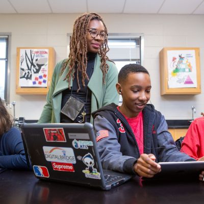 A teacher helps students during a coding lesson at Sutton Middle School.