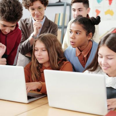 Students around laptops in a classroom.