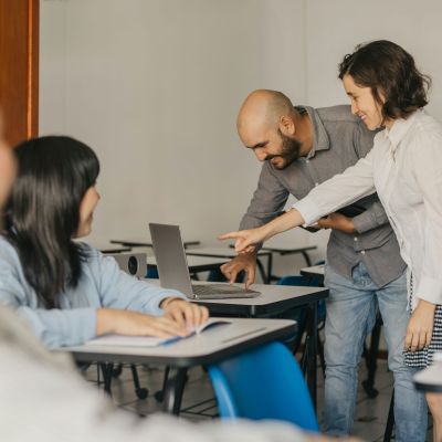 Teacher looking at a laptop with some students.