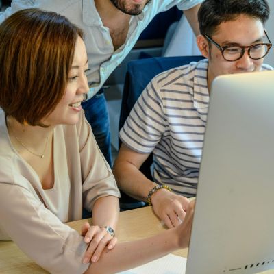 Three people looking at a monitor together.